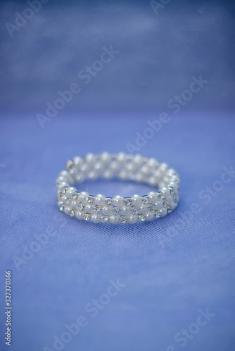 Jewelry for the bride: a bracelet with pearl beads on a blue-purple background. Selective focus