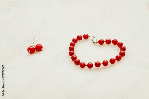 Red jewelry: bracelet and earrings with beads on a white background