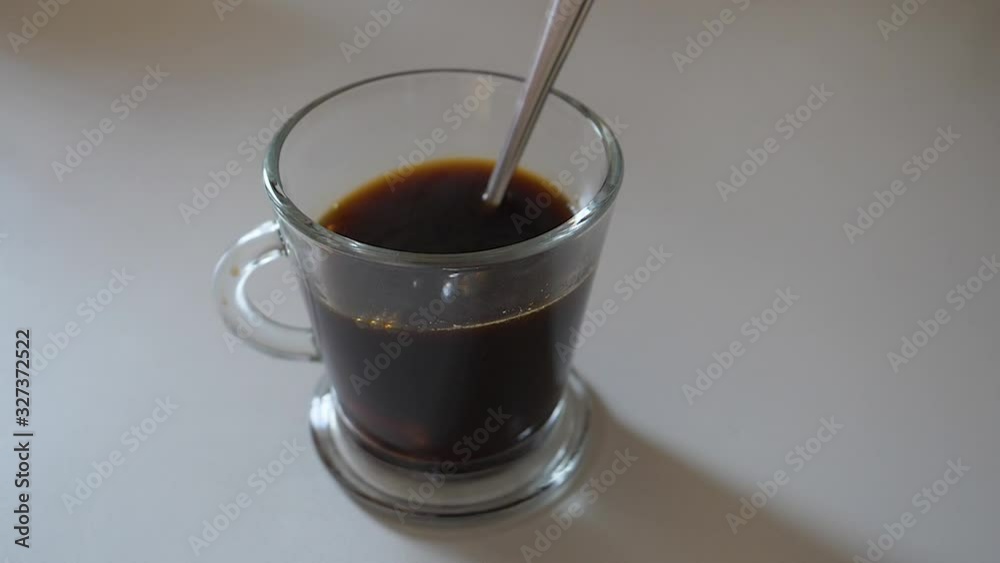 UNE PIERRE DE SUCRE TOMBANT AU RALENTI DANS UNE TASSE DE CAFÉ