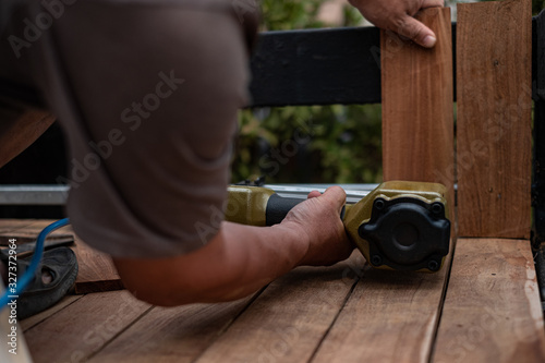 Tablou canvas Hand man carpenter using air nail gun to complete wood table in garden