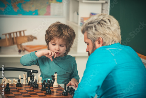 Happy family. Teacher and schoolboy playing chess in class. Child early development.