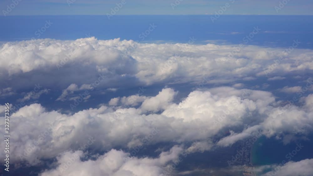Flying over clouds above beach, view to skies from commercial airplane window Flying over clouds above beach, view to skies from commercial airplane window
