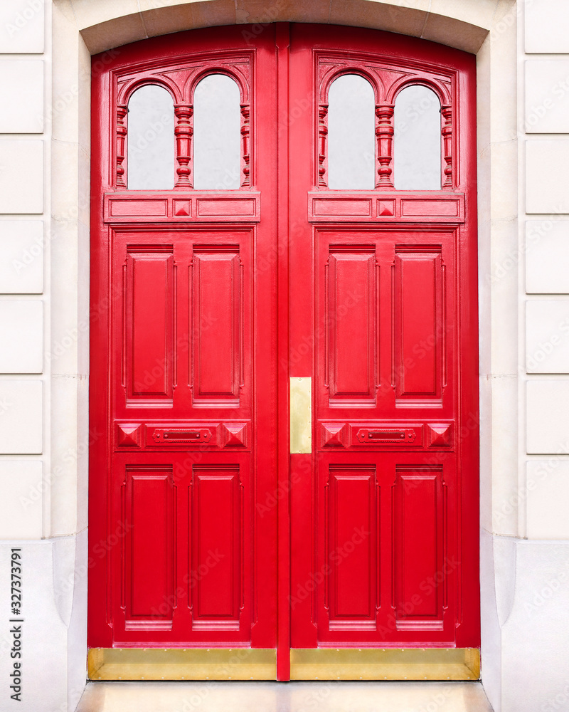 White wall of the house with a closed red wooden door in Paris, France.