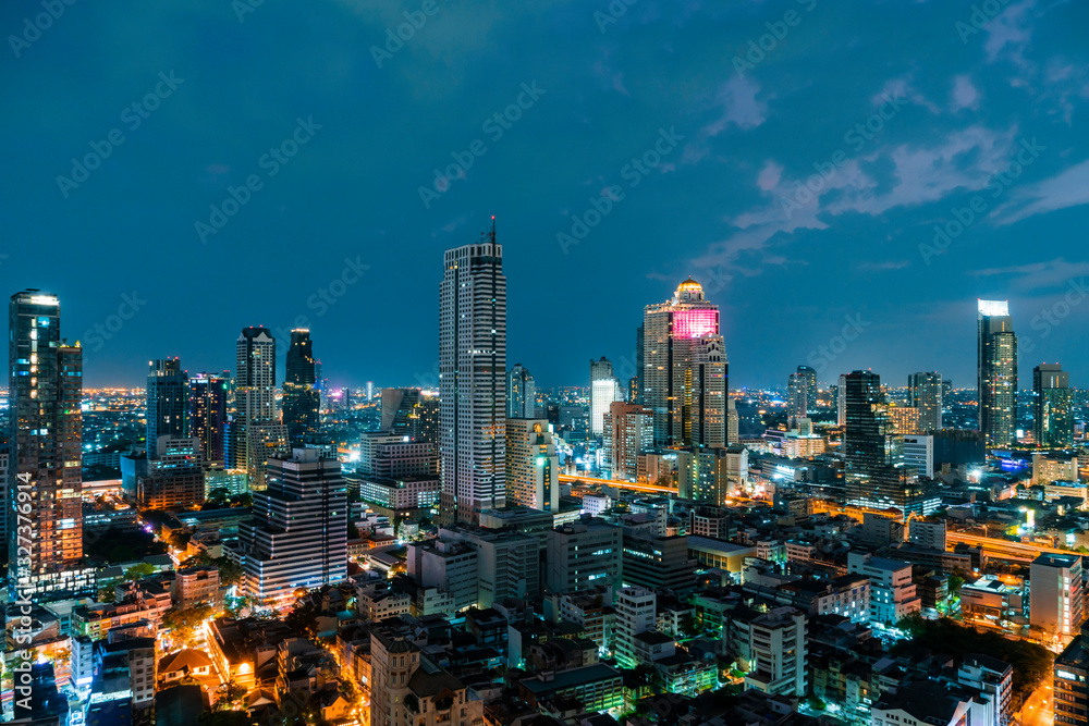 Aerial cityscape of picturesque Bangkok at night time from rooftop. Panoramic evening skyline of the biggest city in Thailand. The concept of metropolis.