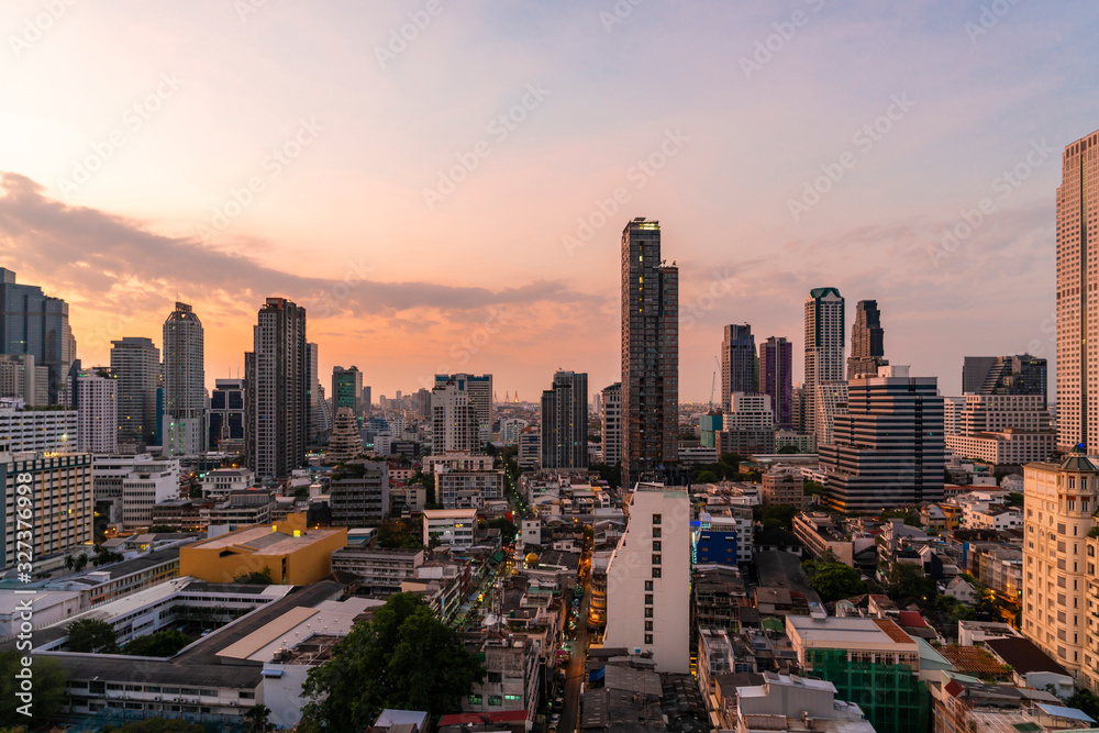 Aerial cityscape of picturesque Bangkok at sunset from rooftop. Panoramic sunrise skyline of the biggest city in Thailand. The concept of metropolis.