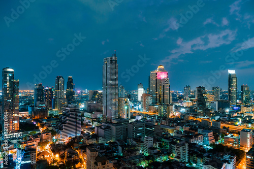 Aerial cityscape of picturesque Bangkok at night time from rooftop. Panoramic evening skyline of the biggest city in Thailand. The concept of metropolis.