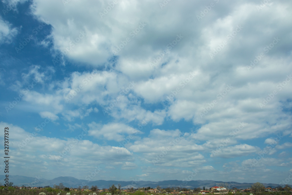 Beautiful cloudscape over a town with houses, blue sky and white clouds, outdoors