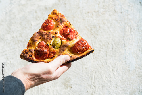 hand showing piece of pizza margherita photo