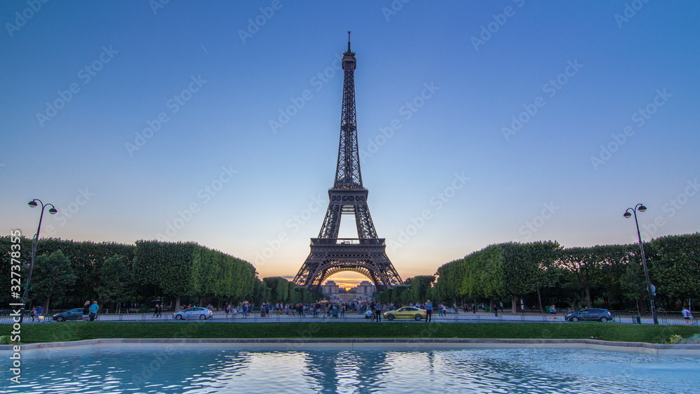 Fototapeta premium Eiffel Tower day to night timelapse and people sitting on the grass in the evening in Paris, France