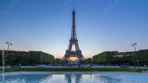 Eiffel Tower day to night timelapse and people sitting on the grass in the evening in Paris, France
