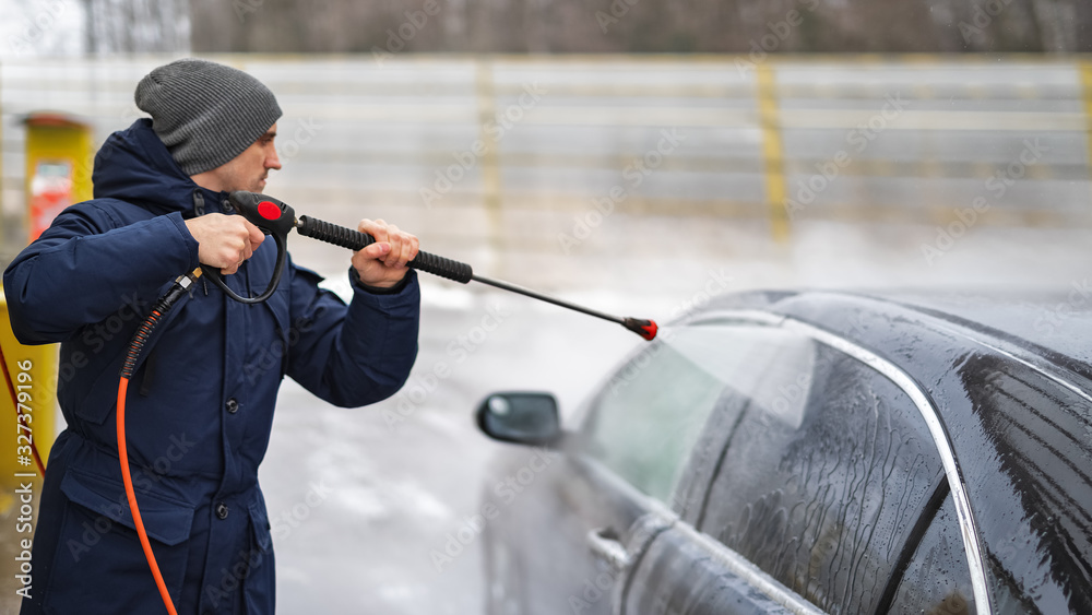 Shot of a man washing his car under high pressure water outdoors. Shot of a man washing his car under high pressure water outdoors.