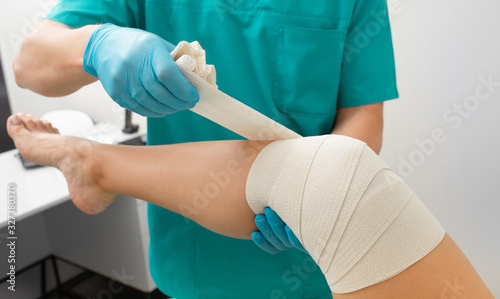 Canvas Print Patient's knee bandaging process with an elastic bandage to fix the knee in a fixed position
