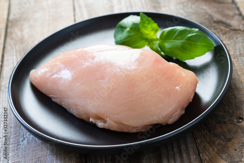 Raw chicken breasts with spices on wooden background