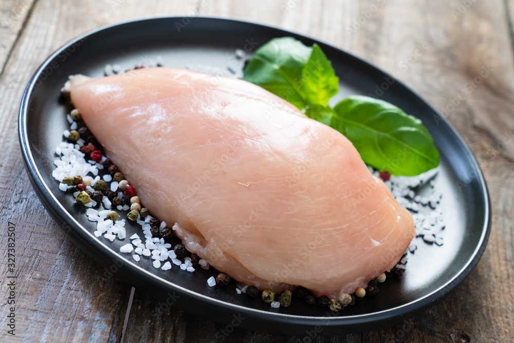 Raw chicken breasts with spices on wooden background Raw chicken breasts with spices on wooden background