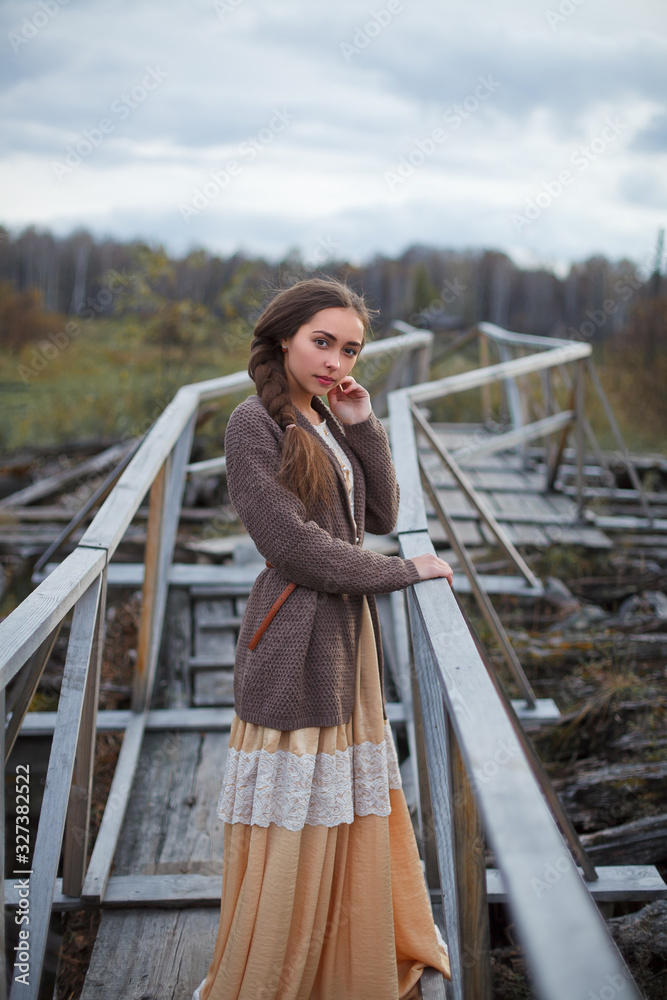 girl in vintage dress stands on a bridge