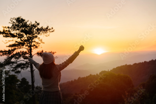 Young woman traveler looking at sunrise over the mountain