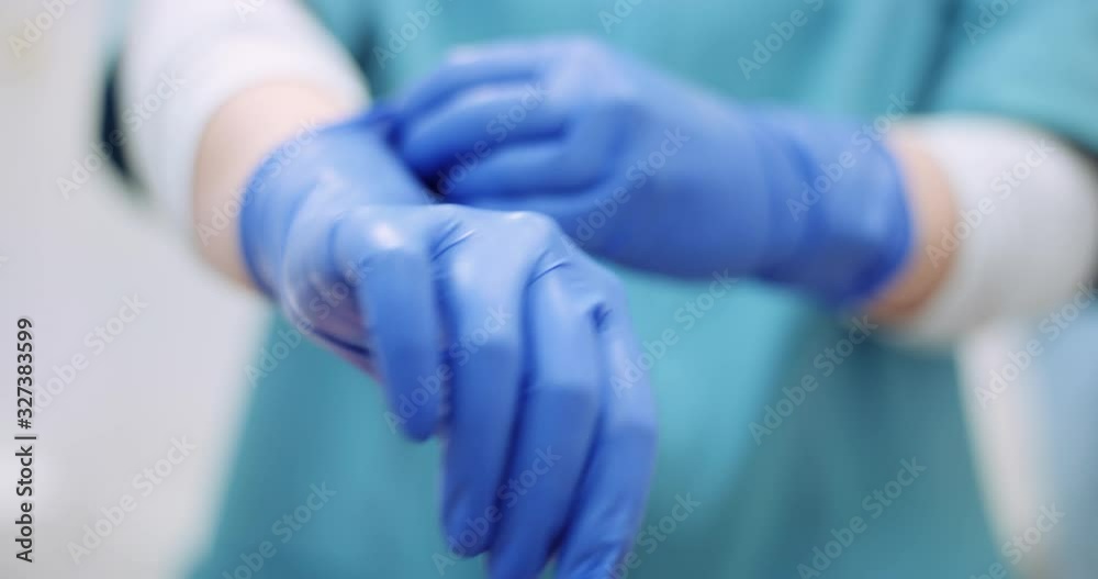 female surgeon putting on protective gloves