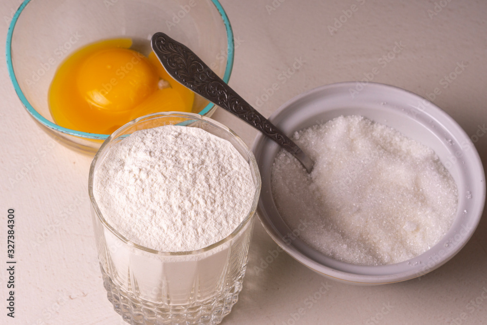 Ingredients for homemade pie stand on the table. Flour, sugar and egg. Close-up. Ingredients for homemade pie stand on the table. Flour, sugar and egg. Close-up.