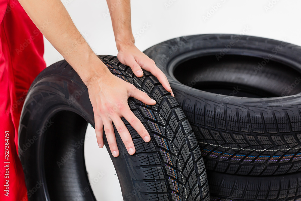 Fototapeta premium Mechanic Holding Car Tire on a white background
