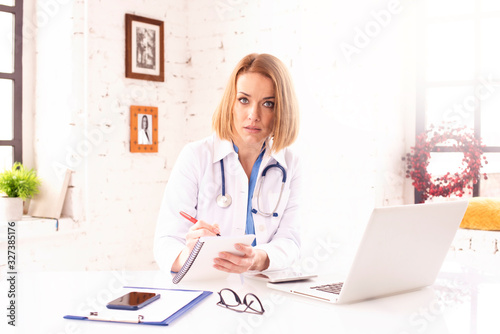 Mature female doctor doing making notes while working in doctor's office