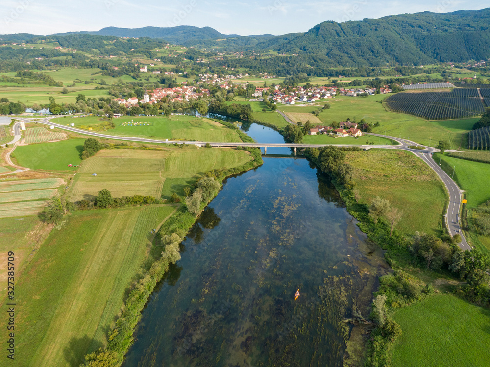 Obraz premium DRONE: Flying high above a group of friends paddling a canoe down river Krka