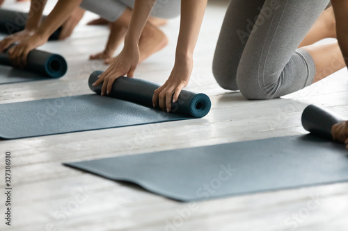 Group of women fold up mats after yoga work out close up