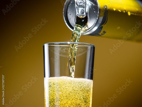 Carbonated energy drink pouring from an aluminum can into a glass