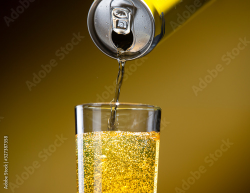 Carbonated energy drink pouring from an aluminum can into a glass