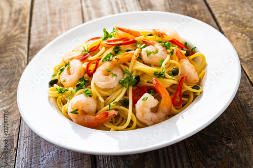 Pasta with prawns and vegetables on wooden background