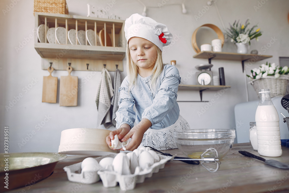 Child in a kitchen. Little girl with a dough. Kid in a blue shirt and white shef hat Child in a kitchen. Little girl with a dough. Kid in a blue shirt and white shef hat