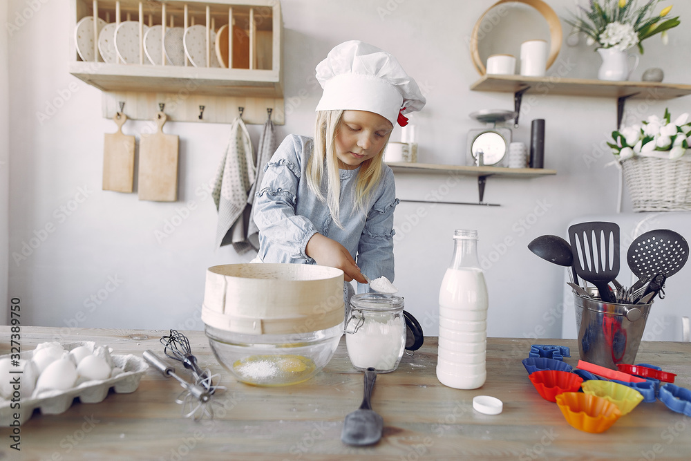 Child in a kitchen. Little girl with a dough. Kid in a blue shirt and white shef hat Child in a kitchen. Little girl with a dough. Kid in a blue shirt and white shef hat