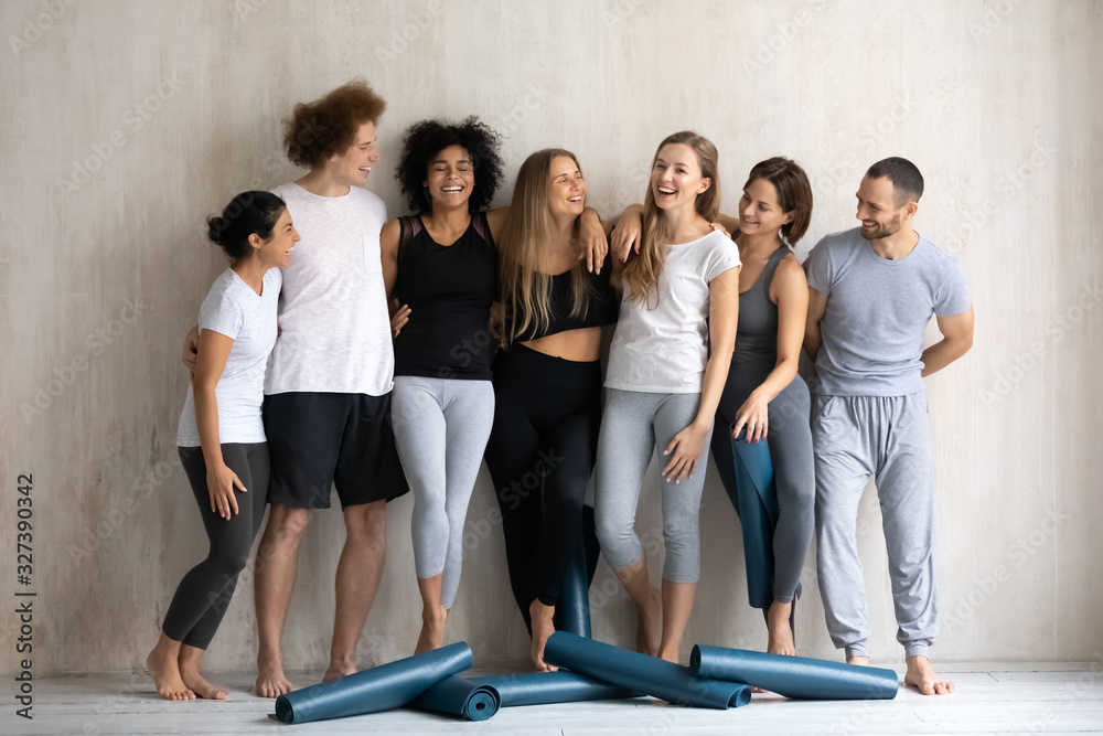 Seven diverse people wearing sportswear wait for yoga class training