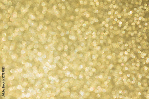 Abstract defocused background texture with golden sparkling glitter. Festive blurred backdrop for greeting cards and other design