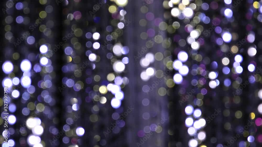 Light illumination from a garland of flashing lights in the form of bokeh of white, purple and gold. The concept of a holiday, Christmas, illumination, party