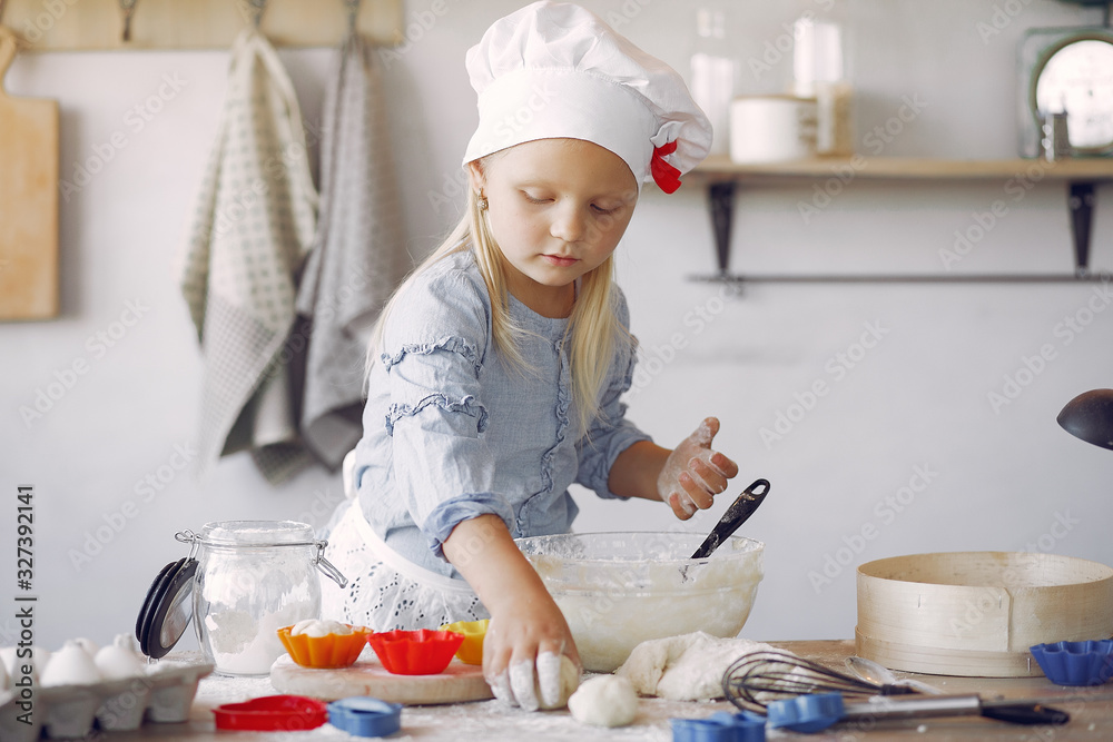 Child in a kitchen. Little girl with a dough. Kid in a blue shirt and white shef hat. Girl with cupcake shape. Child in a kitchen. Little girl with a dough. Kid in a blue shirt and white shef hat. Girl with cupcake shape.