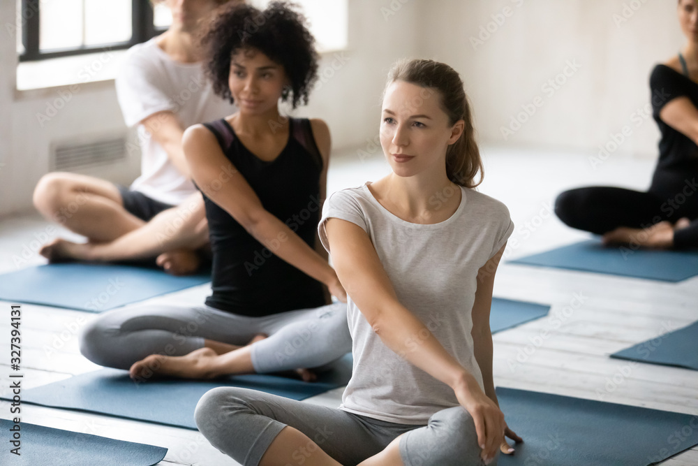 Group of people doing Easy Pose with Twist yoga indoors