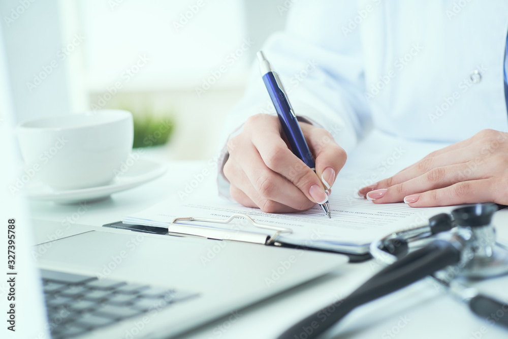 Fototapeta premium Mid section of female doctor writes prescription to patient at worktable. Panacea and life save, prescribing treatment.