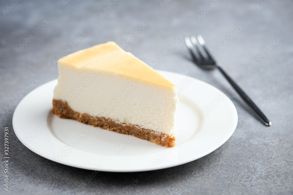 Slice of plain cheesecake on white plate and for for eating isolated on concrete background Slice of plain cheesecake on white plate and for for eating isolated on concrete background
