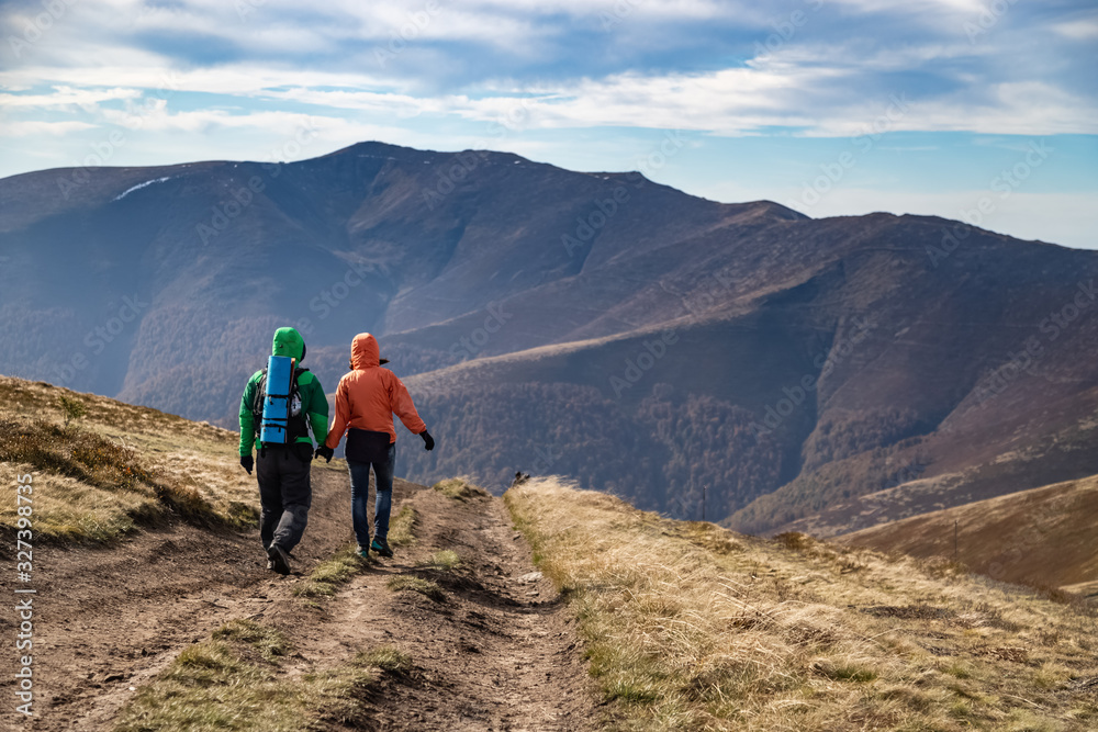 Fall. Couple Backpackers hiking on the path in mountains during autumn. Fall. Couple Backpackers hiking on the path in mountains during autumn.