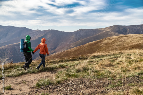 Fall. Couple Backpackers hiking on the path in mountains during autumn.