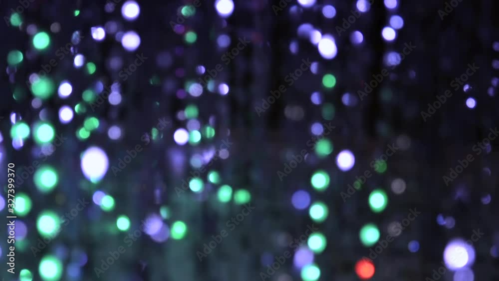 Light illumination from a garland of flashing lights in the form of bokeh white, turquoise, red and purple. The concept of a holiday, Christmas, illumination, party