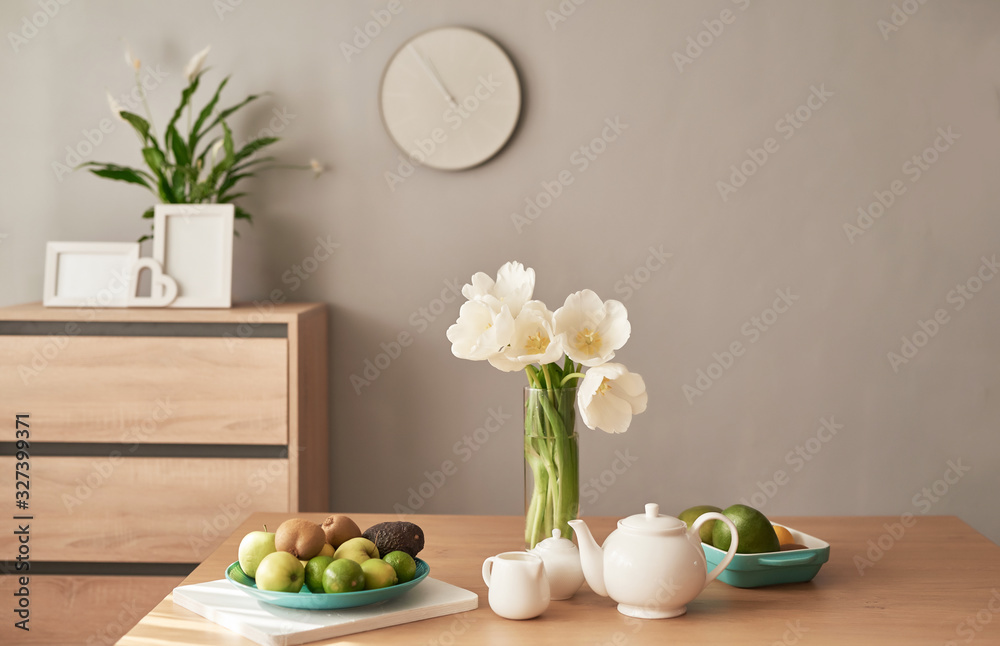 Beautiful tea service on wooden table. Home interior decor, bouquet of flowers in vase, table with set of teapot. Good morning concept. English breakfast. Breakfast at hotel room. Copy space