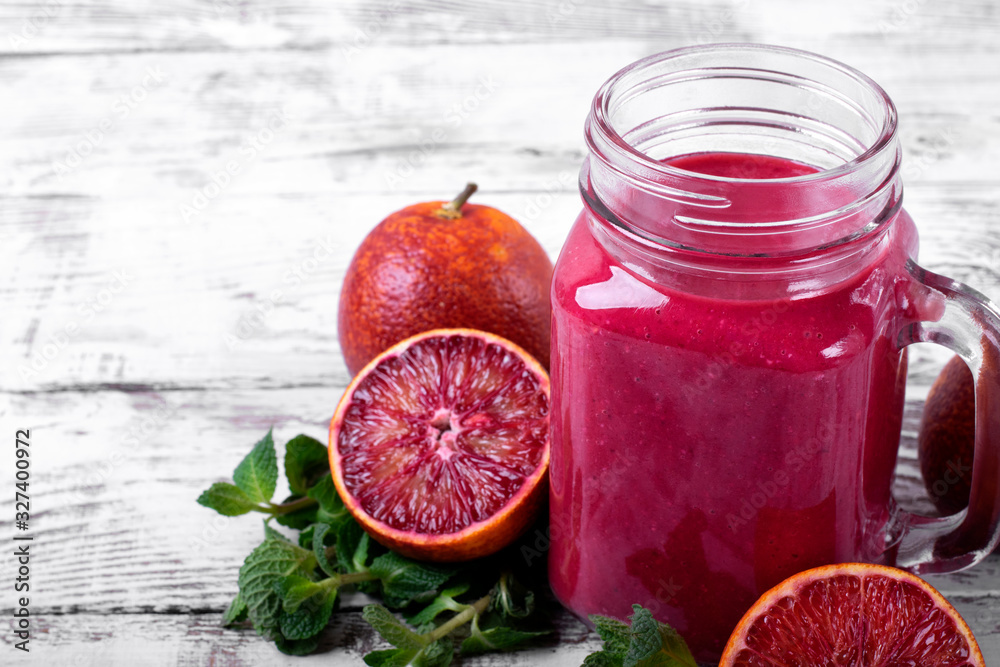 Smoothie with blood orange juice in the mason jar on the white wooden table Smoothie with blood orange juice in the mason jar on the white wooden table