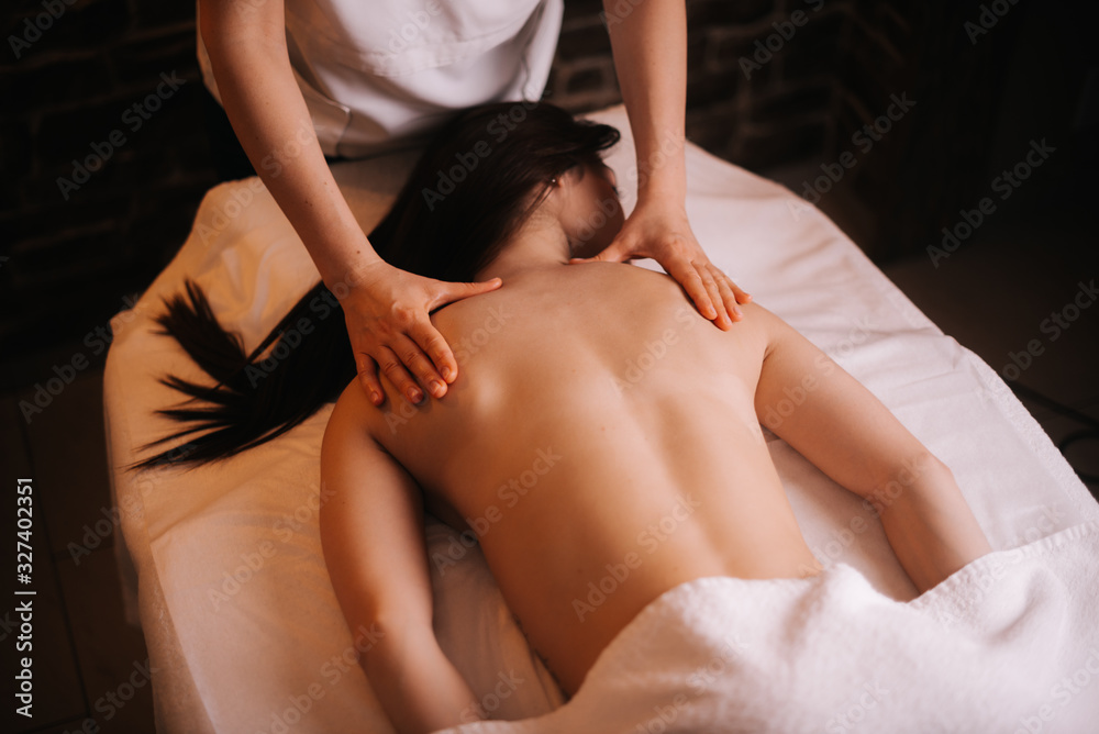 Fototapeta premium Beautiful naked girl with perfect skin gets professional shoulder massage in spa salon. Beautiful naked girl with perfect skin gets relaxing massage. Concept of luxury professional massage.