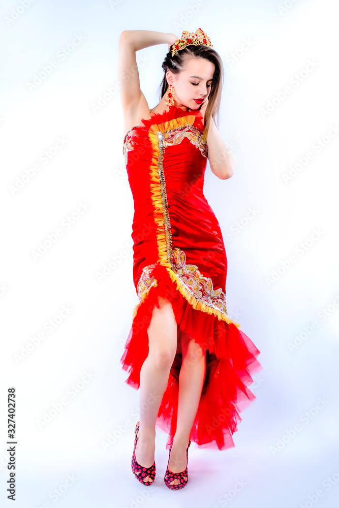 Fashion photo of a beautiful elegant brunette woman in a carnival sexy red dress, high heels posing over gray background. Christmas carnival photo. Isolate Fashion photo of a beautiful elegant brunette woman in a carnival sexy red dress, high heels posing over gray background. Christmas carnival photo. Isolate