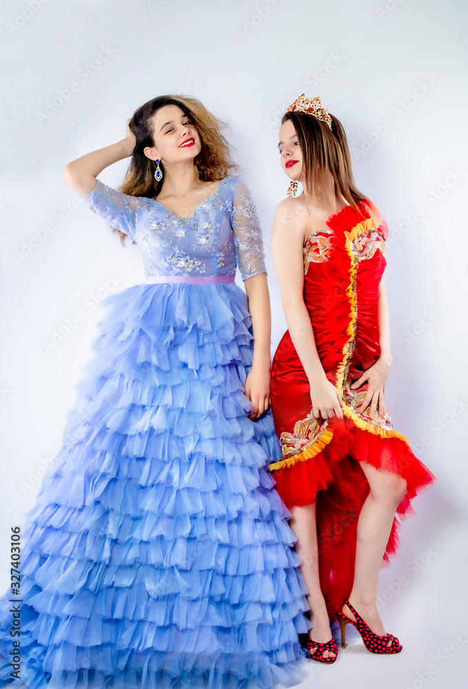 Cute young women wearing magnificent blue and red dresses. Sisters-friendly scenery. Carnival concept. Isolate Cute young women wearing magnificent blue and red dresses. Sisters-friendly scenery. Carnival concept. Isolate