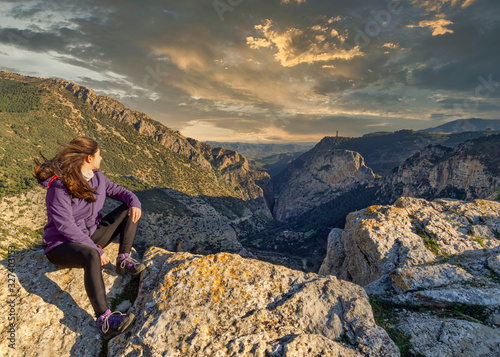 Woman on the edge of a cliff watching the sunset