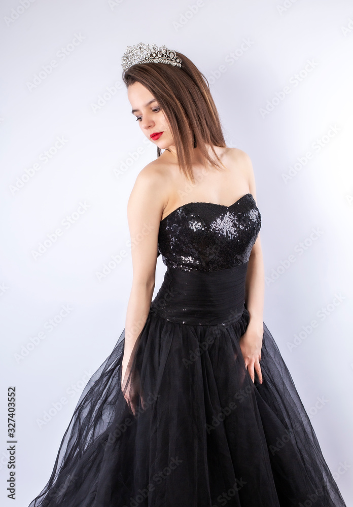 Portrait of a seductive caucasian woman in an elegant black dress on a gray background. Isolated
