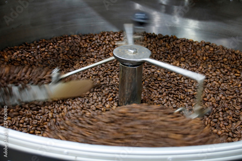 The freshly roasted coffee beans from a large coffee roaster being poured into the cooling cylinder. Motion blur on the beans.
