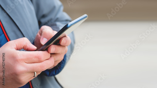 Man s hands with smartphone. Man is texting to somebody. Background with copy space.